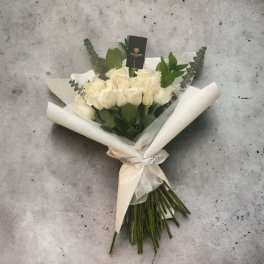 Bouquet of white roses wrapped in white paper with a ribbon