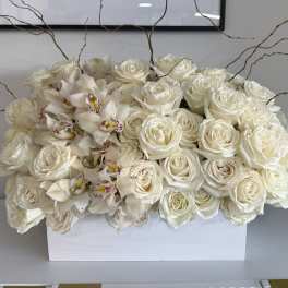 White roses and orchids arranged in a rectangular white box