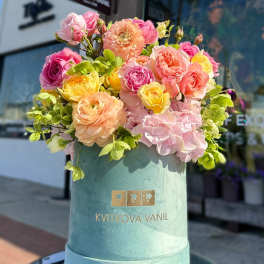 Mixed bouquet of pink, peach, and yellow roses in a teal hatbox