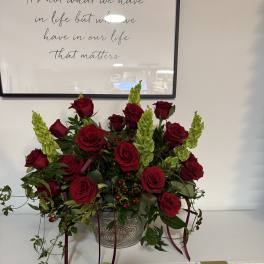 Red roses and green spikes arranged in a metal container