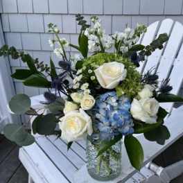 White roses and blue hydrangea in a glass vase