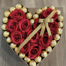 Heart-shaped box with red roses and gold-wrapped chocolates tied with a glitter ribbon