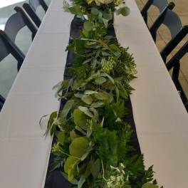 Long greenery garland with white roses on a banquet table