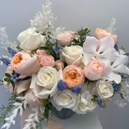 Bouquet of white and blush roses with white orchids in a vase