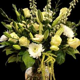 White and pale yellow floral arrangement in a clear glass vase