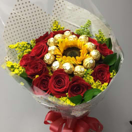 Bouquet of red roses with a sunflower center and gold-wrapped chocolates