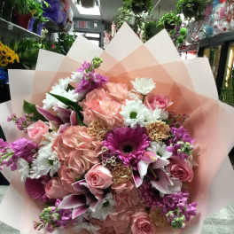 Large bouquet of pink and white flowers wrapped in pale pink paper