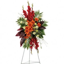 Tall floral standing spray with red and orange flowers on a metal easel