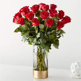 Bouquet of red roses in a clear glass vase with a gold base