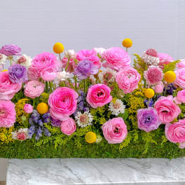 Long rectangular floral arrangement with pink and lavender blooms