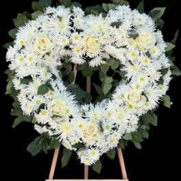 Heart-shaped white floral wreath on a wooden easel