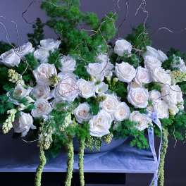 White roses arranged with green foliage in a low container