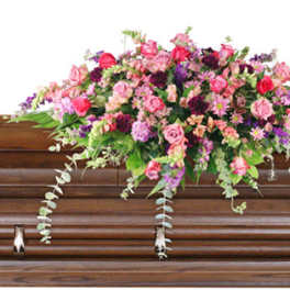 Pink and purple floral spray on a wooden casket