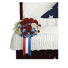 Red, white, and blue floral arrangement on a white-draped casket