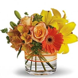 Orange roses and yellow lilies in a clear glass vase