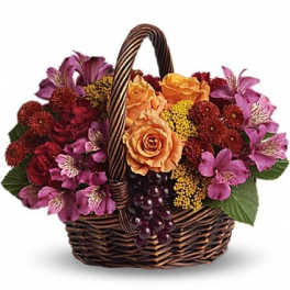 Basket of orange and purple flowers with grapes