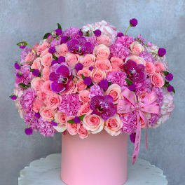 Pink rose and orchid arrangement in a round pink box
