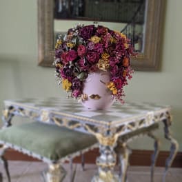 Pink vase with a dense arrangement of dried flowers and berries