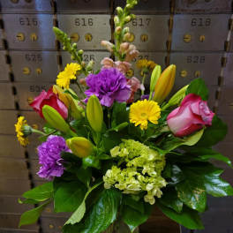 Mixed bouquet of lilies, roses, carnations, and yellow daisies in a glass vase
