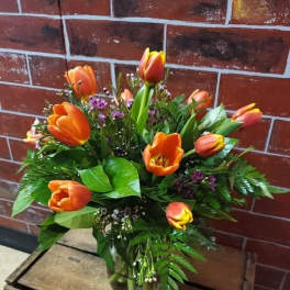 Orange tulips arranged in a clear glass vase