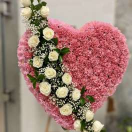 Heart-shaped pink floral arrangement with a diagonal line of white roses