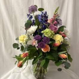 Mixed bouquet in a clear glass vase with purple, pink, yellow, and white flowers