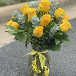 Yellow roses in a glass vase with a yellow ribbon