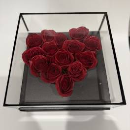 Heart-shaped arrangement of red roses in a clear square box