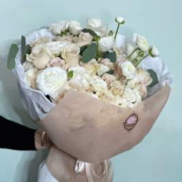 Bouquet of white and blush roses wrapped in beige paper