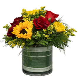 Bouquet of red roses and yellow sunflowers in a glass vase