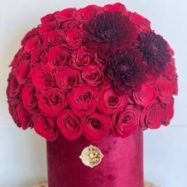 Red rose bouquet in a velvet hatbox with dark burgundy flowers