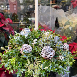 Holiday centerpiece with a white taper candle and evergreen arrangement