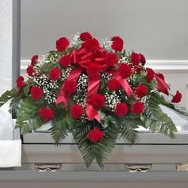 Red floral casket spray with ribbon and greenery