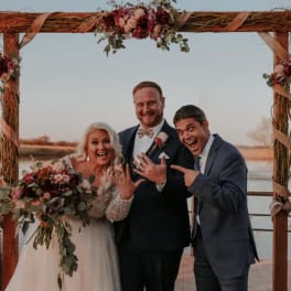 Wedding couple posing under a floral arch with bouquets and arrangements