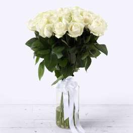 Bouquet of white roses in a clear glass vase with a white ribbon