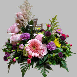 Pink and purple floral arrangement with a silver cross centerpiece