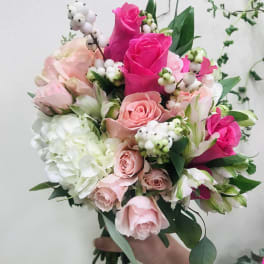 Handheld bouquet of pink and white roses with white berries