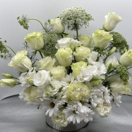 White and pale green floral arrangement in a silver vase