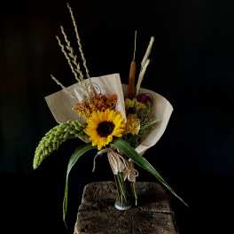 Bouquet with a sunflower and dried grasses in paper wrap