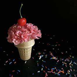 Pink carnations in a waffle cone with a cherry on top