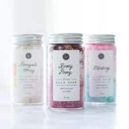 Three labeled jars of bath salts in pastel colors
