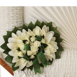 White floral bouquet with green ribbon accents on a white quilted surface