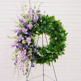 Purple floral wreath on a stand with trailing blooms