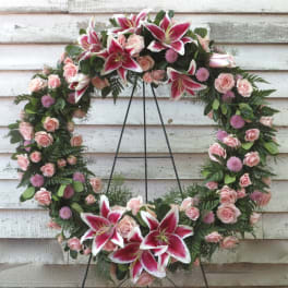 Heart-shaped floral wreath with pink roses and lilies on a stand