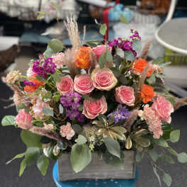 Mixed pink and orange flower arrangement in a wooden box