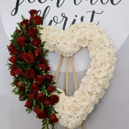Heart-shaped floral wreath of red and white roses on an easel