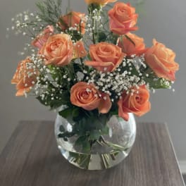 Peach roses arranged in a clear glass vase with baby's breath