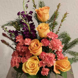 Orange roses and pink carnations in a glass vase