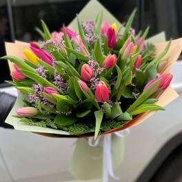 Bouquet of pink and yellow tulips with purple filler flowers