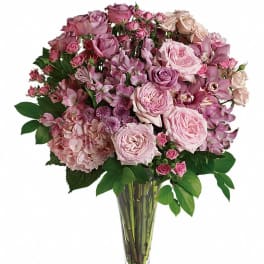 Pink rose and orchid bouquet in a clear glass vase
